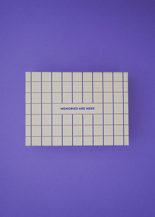 Pudełko pamięci Endless Hugs – Pudełko wspomnień dla niemowląt w kratę - Butter ma niebieską kratkę i napis „MEMORIES ARE Here” na wieczku, dzięki czemu jest idealnym prezentem dla rodziców i jest prezentowane na jednolitym fioletowym tle.