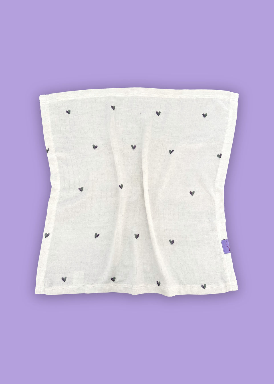 Biała tkanina z małymi czarnymi serduszkami na fioletowym tle, wykonana z hipoalergicznych włókien bambusowych. Produkt: PIELUSZKI MUŚLINOWE Z BAMBUSA - DWUPAK 60x60 CM / SERDUSZKA firmy Endless Hugs.